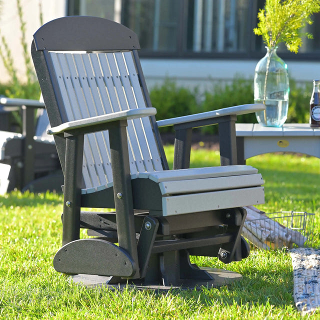 This is a lifestyle image showing the Dove Gray and Black colored swivel glider chair in a grassy yard.