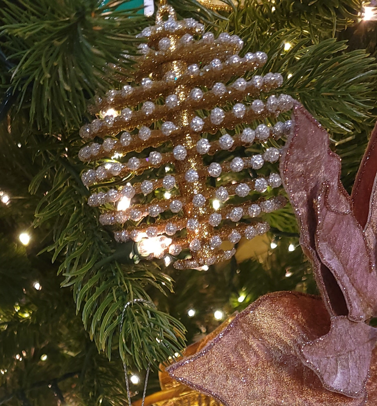 Glitter ornaments shaped like round pine cones. One is silver with gold tips and the other is gold with silver tips.