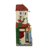 Resin lighted building façade for a Lemax display. Designed to look like a Mexican-style home (Hacienda). There are a lot of signs. Some of them read "Beginner Lessons," "Portrait Studio," "Holiday Special! Free drawing class," "Kids Art, "Cafe," "Holiday Art Sale," "Van's Pottery" and "Art Classes Upstairs." There are people everywhere shopping. There's a man making pottery and a few kids taking pictures with Santa.