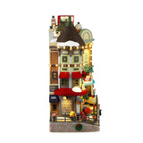 Resin building facade for a Lemax display. Designed to look like a bunch of store fronts. Signs read: "Fay's Flowers & Bouquets," "The Burger Cafe," "Jolly Toys & Games," "Quilter's Island," Sweet Spot" and "Hot Fresh Coffee at the Christmas Bazaar!" There are flowers everywhere and a billboard on the roof advertising a visit with Santa.