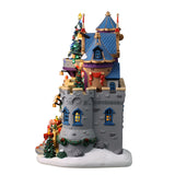 Resin lighted building for a Lemax display. Designed to look like a stone castle decorated for a Christmas gala with Santa. There are people dancing on the balcony and decorative nutcrackers. There are decorated Christmas trees, a snowman and red/white striped candle lights outside.