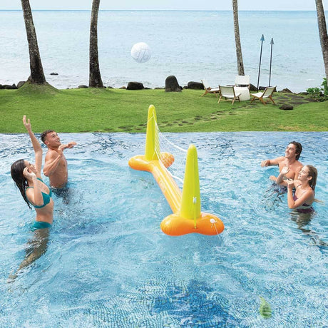This is a lifestyle image showing four people using the inflatable volleyball net and inflatable volleyball in a pool near the beach.