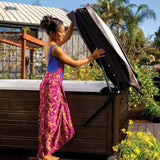 This image shows a woman using the UpRite lift system to lift the cover off of her Hot Springs hot tub.