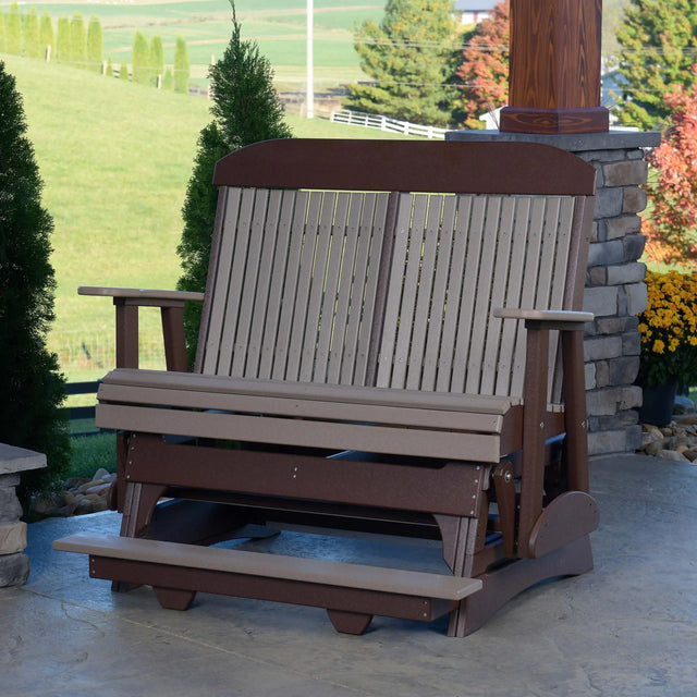 This is the Weatherwood and Chestnut Brown colored classic balcony glider bench on a patio on the side of a house.
