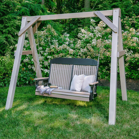 This is a lifestyle image showing the Weatherwood and Black colored swing in a grassy backyard.