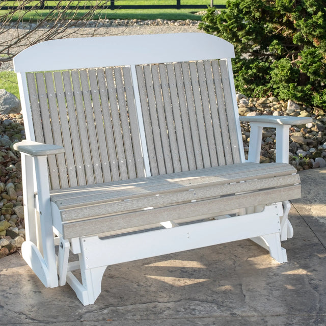 This is a lifestyle image showing the Birch and White colored classic glider bench on a stone patio.