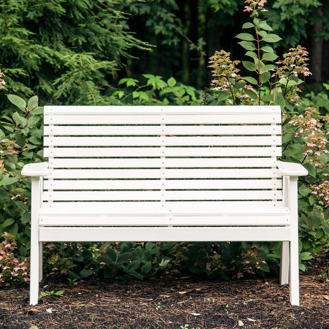 This is a lifestyle image showing the White bench with plants behind it.