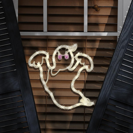This is a lifestyle image showing a lighted ghost silhouette decoration hanging in a window.