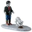 This image shows what this Lemax Spooky Town figurine looks like on a white background. It was designed to look like a young, dead boy wearing a black shirt with a red scarf and ripped blue jeans. He's wearing green socks and brown boots. The boy is looking at a skeleton cat who is looking at a large, brown rat.