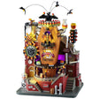 This image shows what this Lemax Spooky Town Sights and Sounds building looks like on a white background. It's designed to look like a brick building built around a large, wooden casket. There are bats circling above. The place is decorated with lots of candy corn accents. There's a conveyor belt with monsters bringing boxes of candy corn.