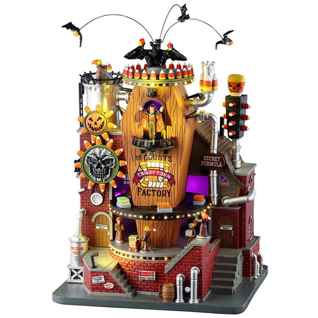 This image shows what this Lemax Spooky Town Sights and Sounds building looks like on a white background. It's designed to look like a brick building built around a large, wooden casket. There are bats circling above. The place is decorated with lots of candy corn accents. There's a conveyor belt with monsters bringing boxes of candy corn.