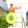 This is a lifestyle image showing a man standing on a lifeguard station holding the neon yellow inner tube.