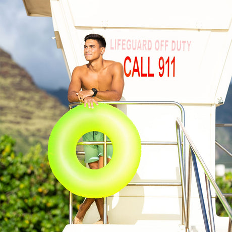 This is a lifestyle image showing a man standing on a lifeguard station holding the neon yellow inner tube.