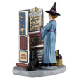 This image shows what this Lemax Spooky Town figurine looks like on a white background. It's designed to look like a witch wearing a light blue robe and a black, pointy hat standing in front of a vending machine. It reads "In a hurry? Spell O' Matic. Love elixirs and lucky charms. 100% fresh." Next to the witch, there's a small black cat with green eyes. On the other side of the witch, there's a basket of ingredients.