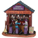 This image shows what this Lemax Spooky Town table accent looks like on a white background. It was designed to look like a bar. The signs read "Spooky Spirits Cafe," "Witching Hour ~ 5 to Midnight," and "Spooky Spirits: Drac's Bloody Mary, Witches Brew, Vampire Vermouth, Poisoned Apple Martini." Behind the bar are various bottles. At the bar, there are two witches toasting their drinks. The lights above the bar are shaped like skulls."