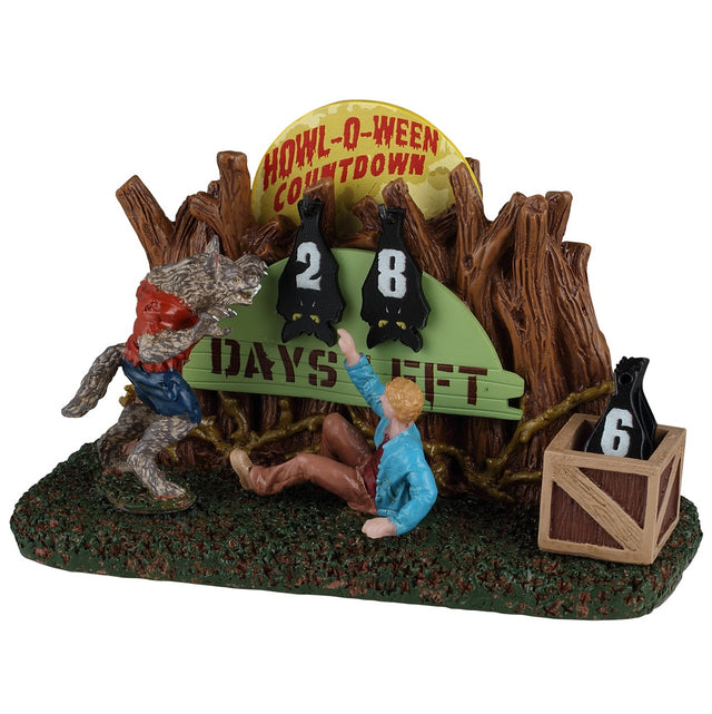 This image shows what this Spooky Town table accent looks like on a white background. The item is a countdown with numbers you can change, counting down to Halloween. There's a werewolf terrorizing a man who is scared on the ground. The moon is peaking out above the trees. The numbers are shaped like bats hanging upside down.