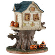 This image shows what this Lemax Spooky Town table accent looks like on a white background. It's designed to look like a pale yellow, semi-dilapidated tree house. It's decorated with jack-o-lanterns.
