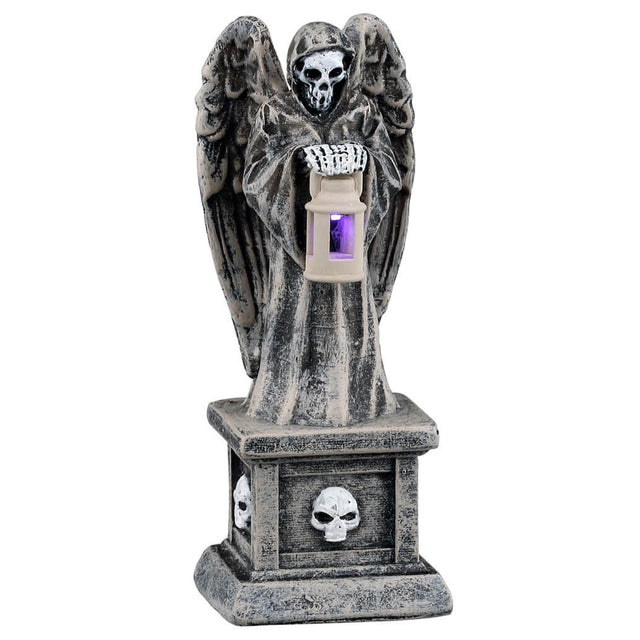 This image shows what this Lemax Spooky Town accessory looks like on a white background. It was designed to look like a tombstone with a skeletal angel on top. The angel is holding a small lantern with a purple light inside.