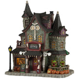 This image shows what this Lemax Spooky Town lighted building looks like on a white background. It was designed to look like a spooky, Victorian-era styled mansion. Above the front door, there's a sign that reads "Frightful Fangs Dentistry." There's also a sign off to the left of the front door that reads "Lycan Root Canal 30% off." There's a window in the front you can look into and see someone in the dentist's chair. Off to the right, there are plants with mouths and lots of jack-o-lanterns.