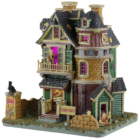 This image shows what this Lemax Spooky Town lighted building looks like on a white background. It was designed to look like an old-timey, dilapidated house. There's a monster standing on the balcony and another monster crawling out from the basement. There's a sign that reads "KEEP OUT," along with lots of boarded up windows and doors.