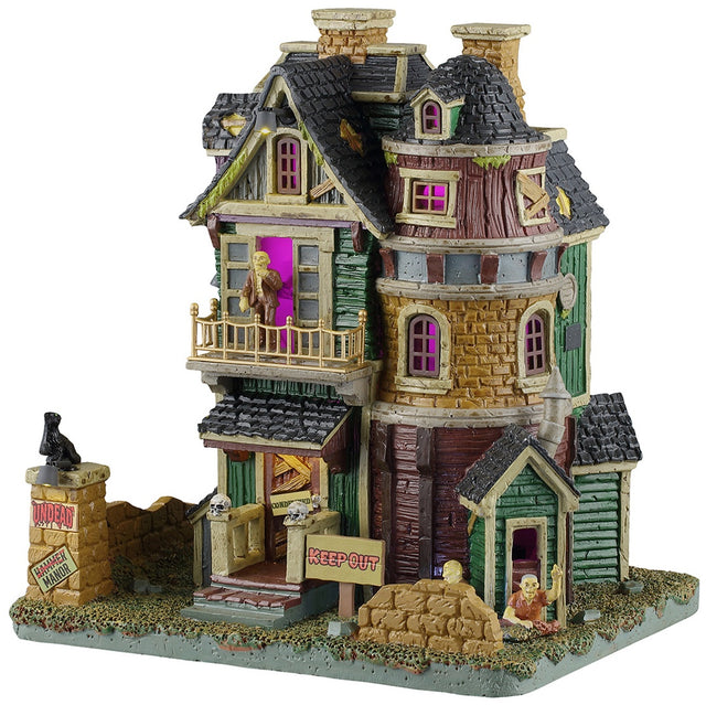 This image shows what this Lemax Spooky Town lighted building looks like on a white background. It was designed to look like an old-timey, dilapidated house. There's a monster standing on the balcony and another monster crawling out from the basement. There's a sign that reads "KEEP OUT," along with lots of boarded up windows and doors.