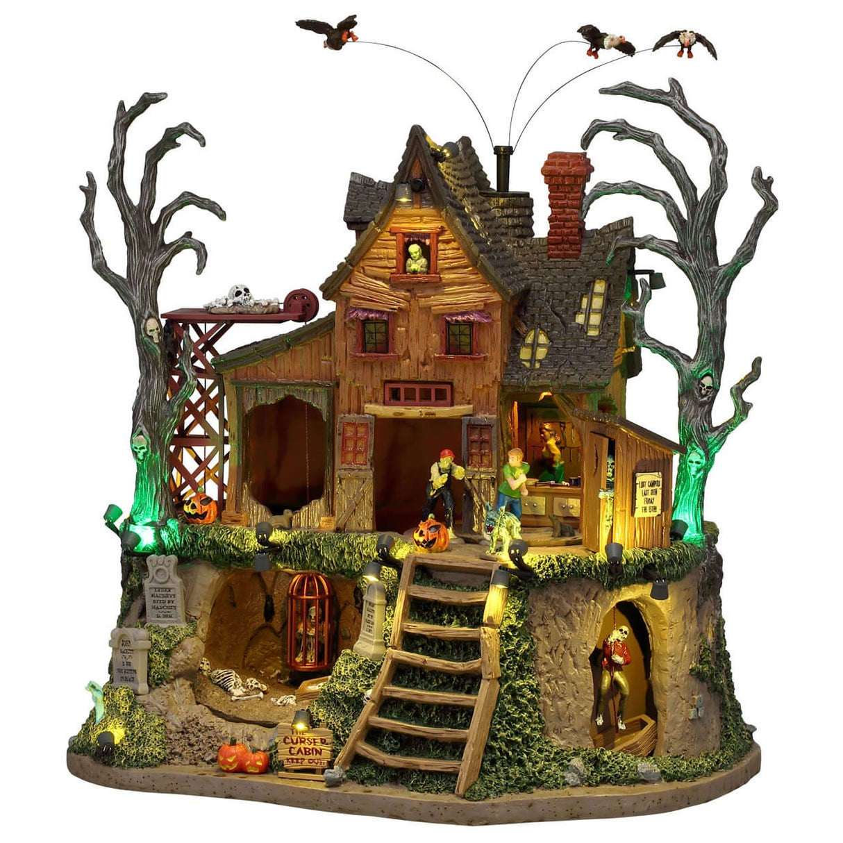This image shows what this Lemax Sights and Sounds building looks like on a white background. It was designed to look like a dilapidated, wooden cabin with bare trees next to it. There are vultures circling above and monsters walking around. You can see the ground underneath the cabin. There's a skeleton in a cage, there are some tombstones and a creaky ladder.