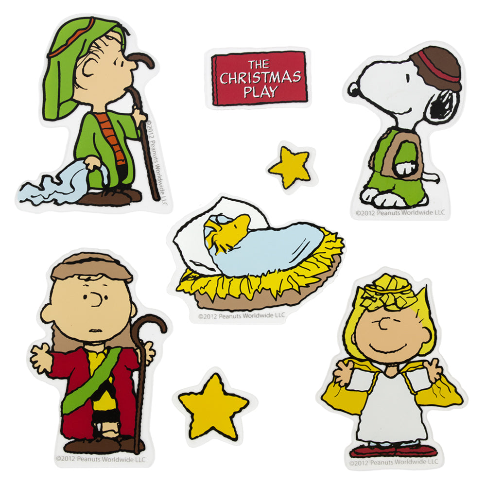 This image shows the Nativity scene Peanuts option. Linus, Charlie Brown and Snoopy are dressed like shepherds. Woodstock is in a manger, like baby Jesus. Sally is dressed as an angel. There are two yellow stars and a red sign that reads "The Christmas Play" in white font. 