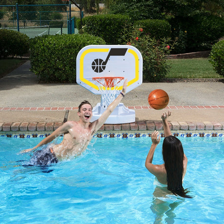 This is a lifestyle image showing two people playing basketball in the pool, aiming the ball for the Utah Jazz themed basketball hoop.