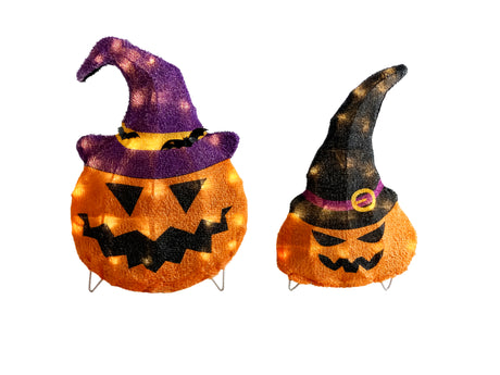 This image shows the two decorative pumpkin sculptures on a white background. The pumpkin on the left is slightly larger than the pumpkin on the right. The pumpkin on the left is wearing a purple and yellow witch hat with two small black bats on it. The pumpkin on the right is wearing a black and purple witch hat with a yellow buckle.