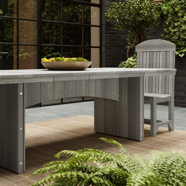 This is a lifestyle image showing the Coastal Gray colored dining table with a matching chair. There's a bowl of green succulents on in the center of the table.