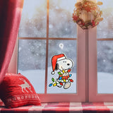 This is a lifestyle image showing the Snoopy decoration hanging in a window while it snows outside.