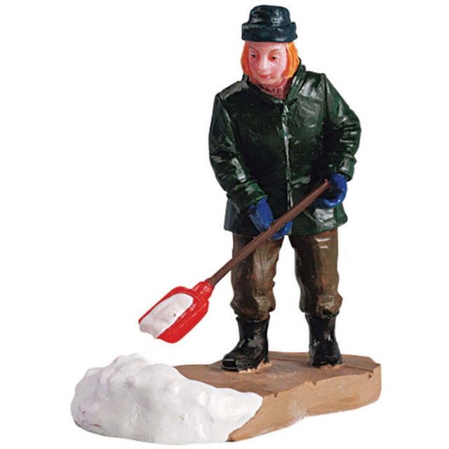 Polyresin figurine for a Lemax display. Designed to look like someone shoveling snow off the sidewalk. They're wearing a dark green hat, a dark green coat, brown pants, black boots and blue mittens. The shovel is red.