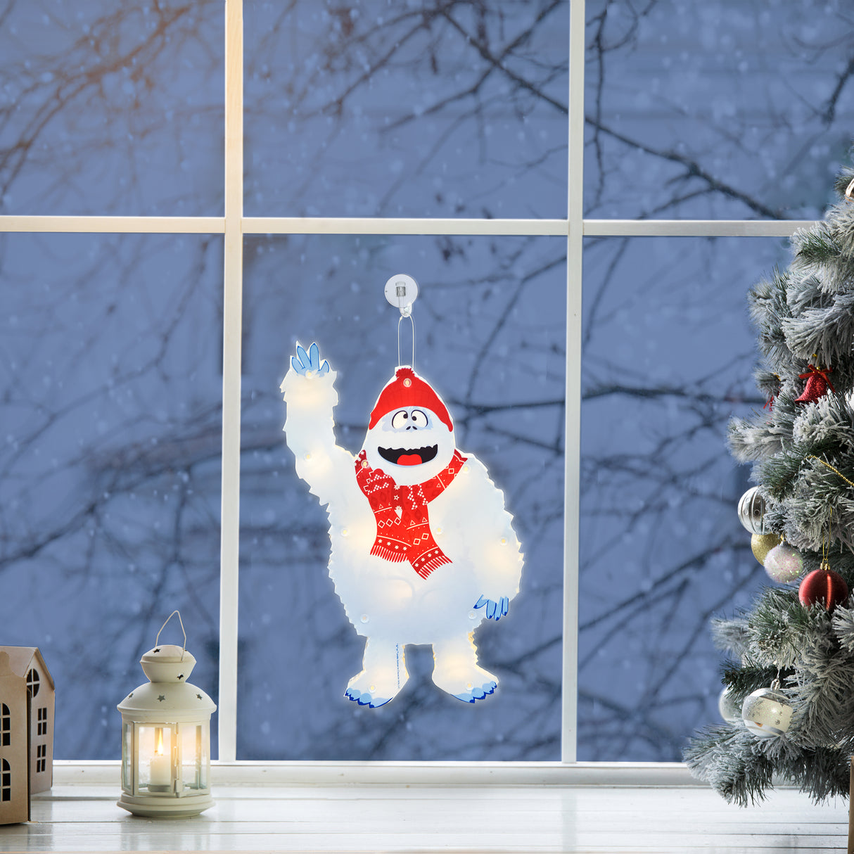 This is a lifestyle image showing the Bumble decoration hanging in a window among other Christmas decorations.