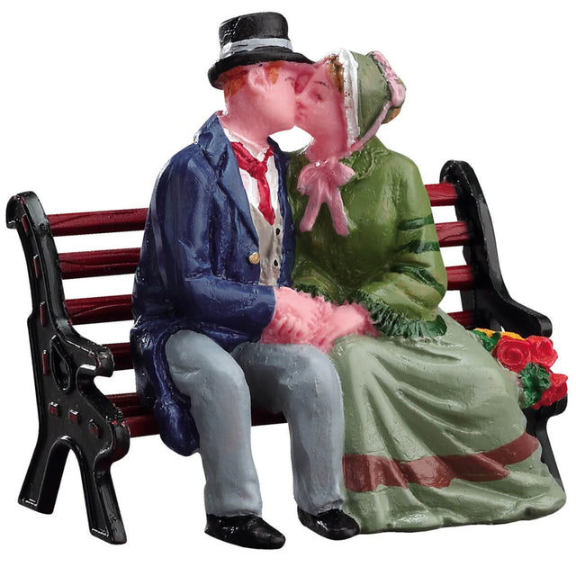 Village accent for a Lemax display. Designed to look like a man and a woman dressed in Victorian-era clothing, sharing a kiss on a wooden bench.