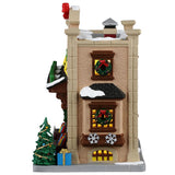 This image shows what the other side of this building looks like. There are three windows, two of which have decorated wreaths on them. You can see a decorated Christmas tree and a blue gift with a gold bow.