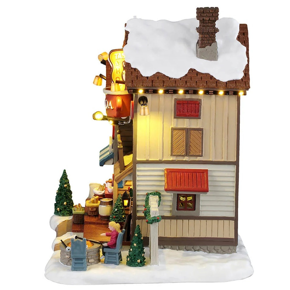 This image shows what the side of this building looks like. There's a woman roasting a marshmallow over a fire pit.