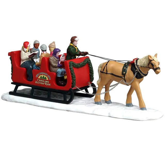 This image shows what this Lemax table accent looks like on a white background. It was designed to look like a horse pulling a sleigh full of people through the snow. The side of the sleigh reads "Pine Mountain Farm Caroling Sleigh Ride." The people in the sleigh are all wearing winter clothes and holding song books.