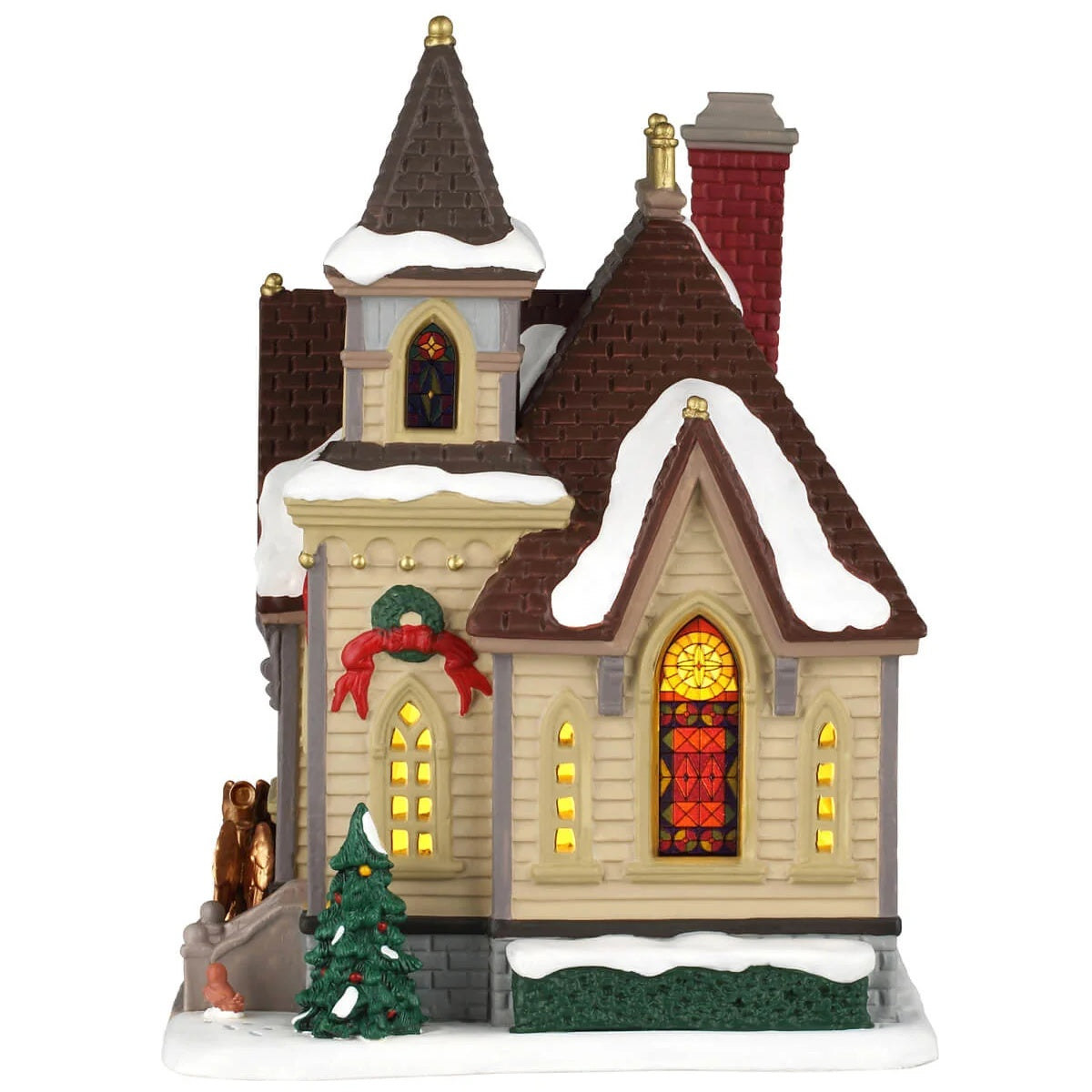 This image shows what this building looks like from the side. There's a stained glass window and a tree that's decorated with ornaments. The roof and the ground are covered in snow.
