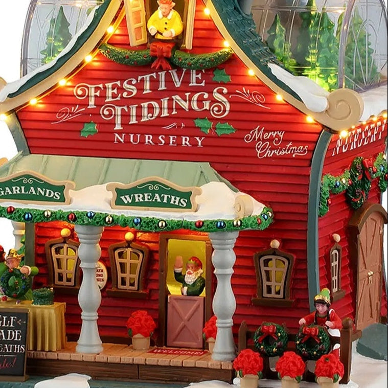 This is an up close view of this lighted building. There's an elf at the front door, waving. The building is decorated with garlands and wreaths.