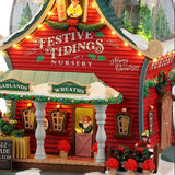 This is an up close view of this lighted building. There's an elf at the front door, waving. The building is decorated with garlands and wreaths.