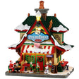 This image shows what this Lemax building looks like on a white background. It was designed to look like a tall house that was turned into an ice cream parlor. The roofs and sidewalk are covered in snow. Santa is eating at one of the tables on the sidewalk and there are elves looking at the menu before ordering at the window.