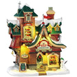 This image shows what this Lemax building looks like on a white background. It was designed to look like a dormitory for Santa's elves. The roofs and the sidewalk are covered in snow. Someone made a snowman on the corner and there are some wild animals standing near it. There's a window near the top of the building where you can see sets of bunk beds with elves sleeping.