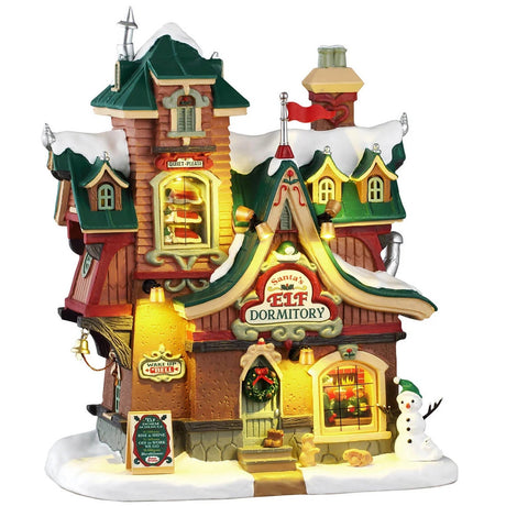 This image shows what this Lemax building looks like on a white background. It was designed to look like a dormitory for Santa's elves. The roofs and the sidewalk are covered in snow. Someone made a snowman on the corner and there are some wild animals standing near it. There's a window near the top of the building where you can see sets of bunk beds with elves sleeping.