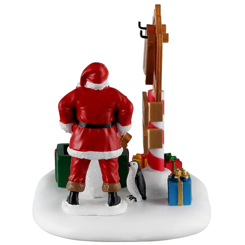 This image shows a side of this table accent. It shows Santa's back, the penguin and some of the gift boxes on the ground.
