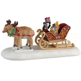 This image shows what this Lemax Santa's Wonderland village table accent looks like on a white background. It was designed to look like two reindeer leading a red and gold sleigh full of toys.