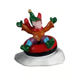 This figurine shows an elf in a red and black inner tube in the snow. The elf is wearing a green hat with a gold bell on the end. He's also wearing a red scarf, an orange sweater, green gloves, purple and blue pants and green shoes.
