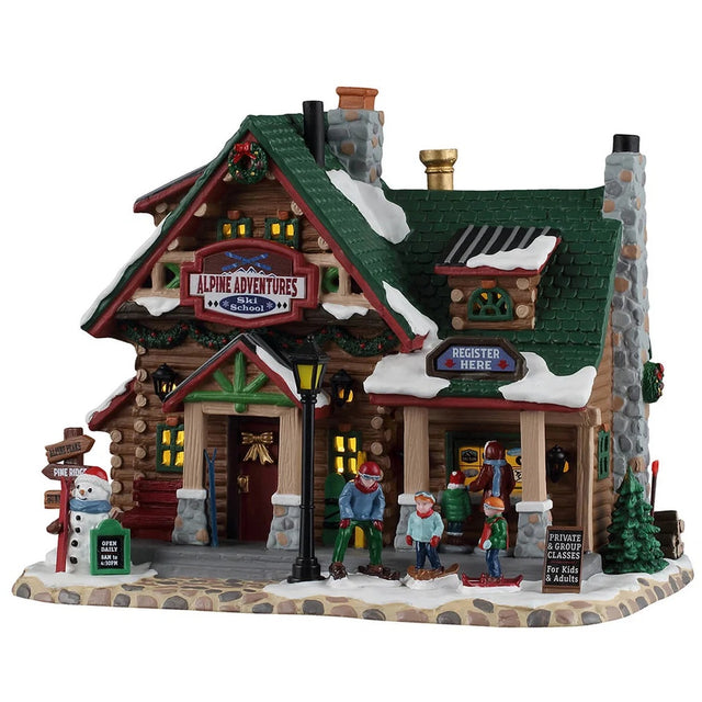 This image shows what this Lemax building looks like on a white background. It was designed to look like a large log cabin turned into a ski school. There's snow on the roof and on the stone sidewalk. There's a snowman on the corner. People are at the counter registering and there are people getting ready to start skiing.