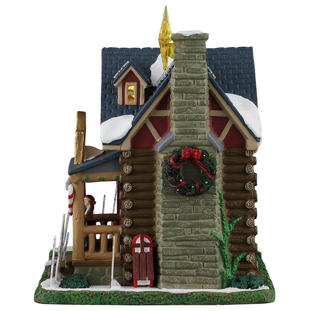 This image shows what the other side of this building looks like. The stone chimney is decorated with a large wreath. There's also a sled leaning against the chimney.