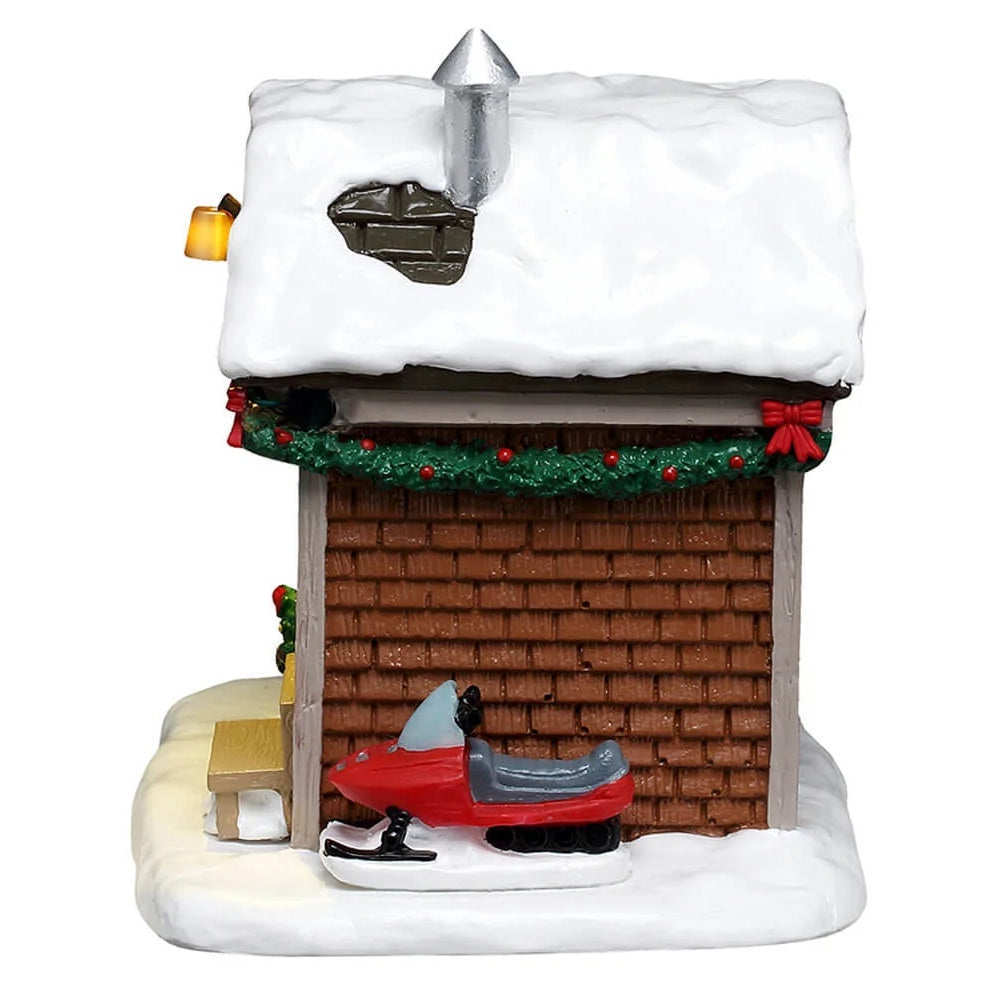This image shows what the side of the house looks like. You can see the green garland with red bows along the roofline and the red snowmobile parked along the house.