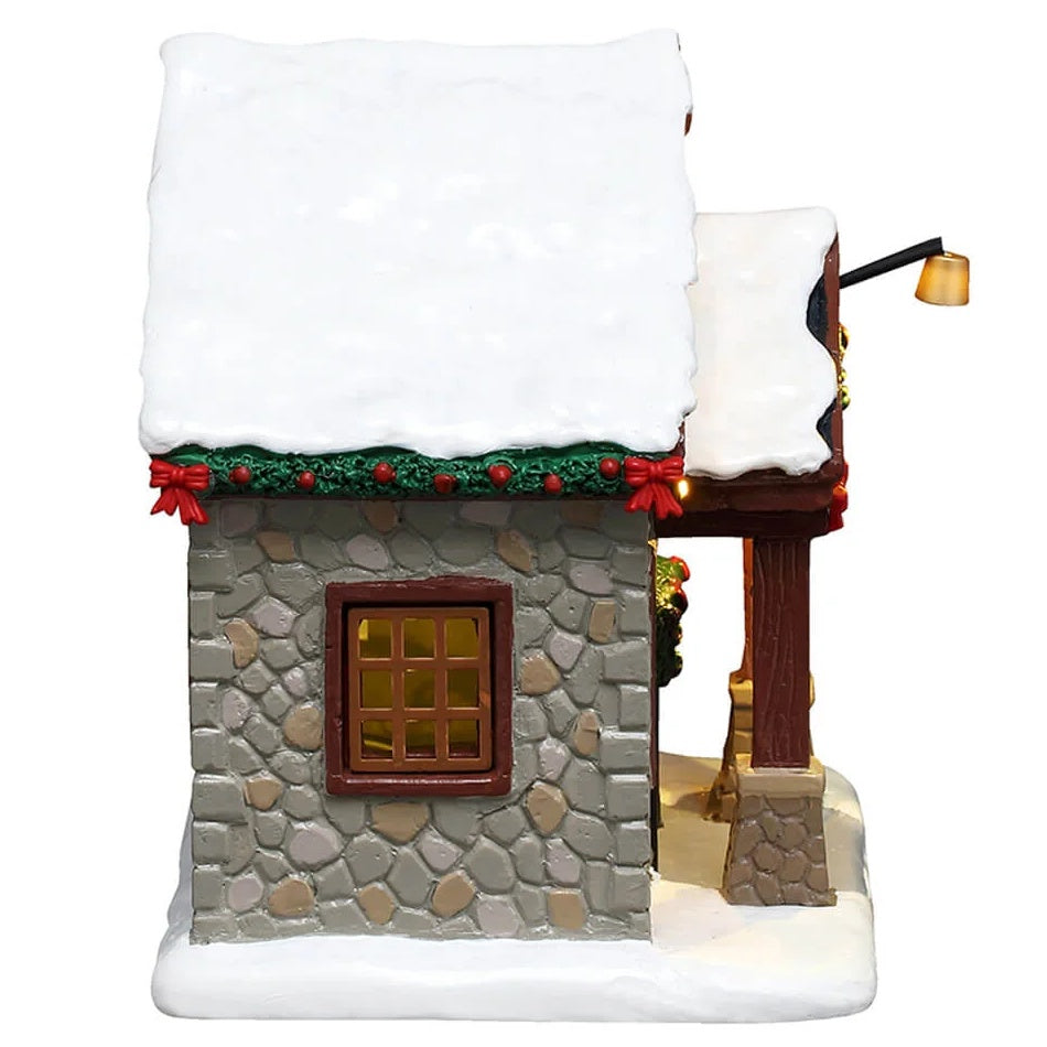 This is image shows what the other side of the house looks like. You can see the green garland with red bows along the roof and a window.